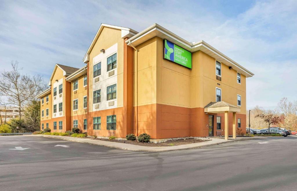 un grand bâtiment jaune avec un panneau vert dans l'établissement Extended Stay America Select Suites - Philadelphia - Malvern - Great Valley, à Malvern