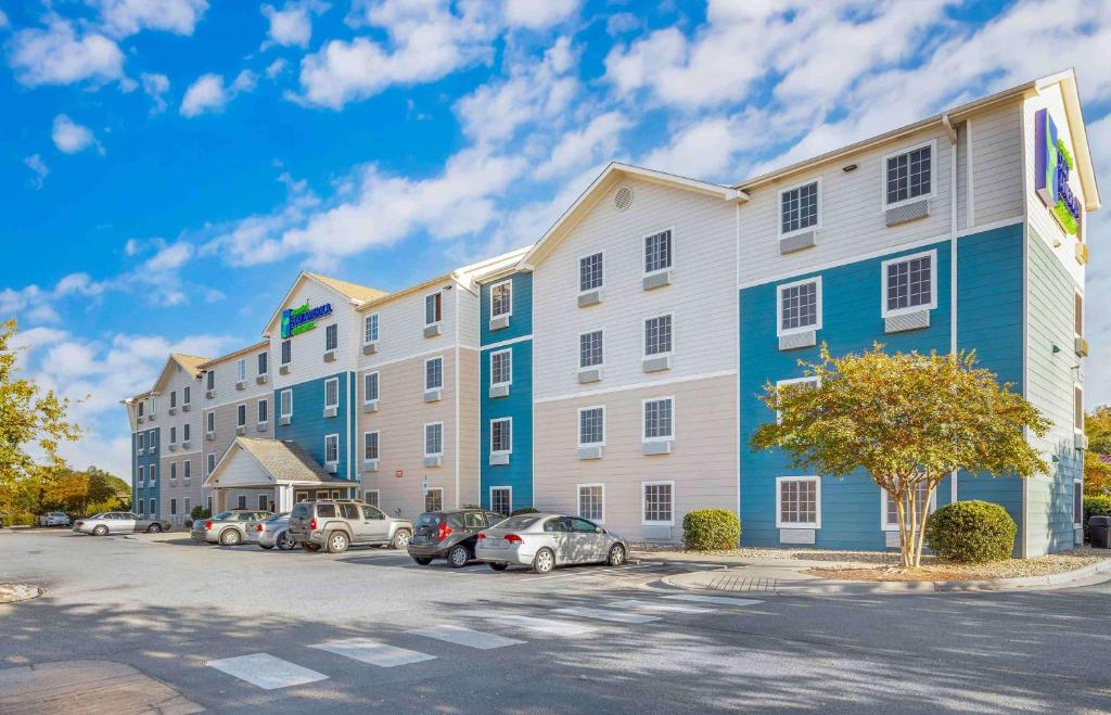un gran edificio de apartamentos con coches aparcados en un aparcamiento en Extended Stay America Select Suites - Wilmington - West, en Wilmington