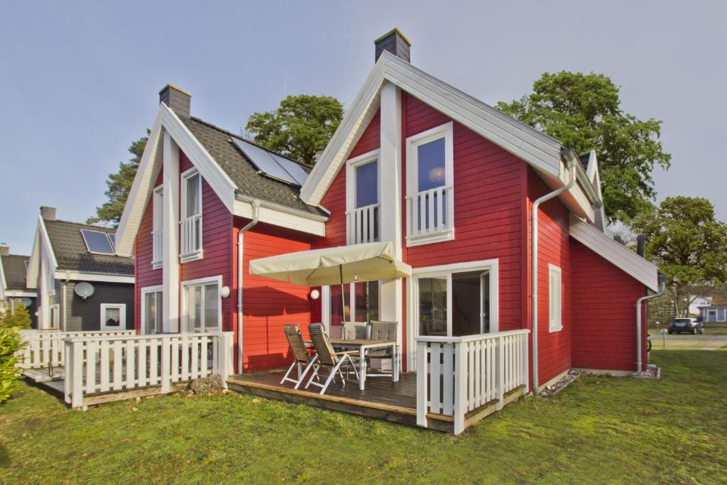 a red house with a deck with a table and chairs at Ferienhaus Wellenläufer Haus - Sauna, Terrasse, Garten in Glowe