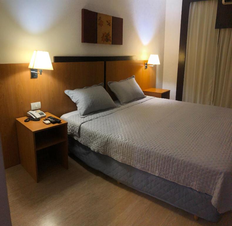 ブラジリアにあるFlat 315 - Comfort Hotel Taguatingaのベッド1台と2泊用のスタンドが備わるホテルルームです。