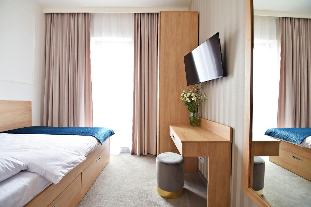 um quarto de hotel com uma cama e uma televisão em IVY Healthy Stay em Konstancin-Jeziorna