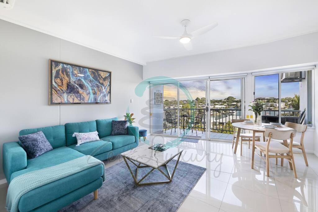 uma sala de estar com um sofá azul e uma mesa em Zen Marina: 1-BR Executive Apartment By The Bay em Larrakeyah