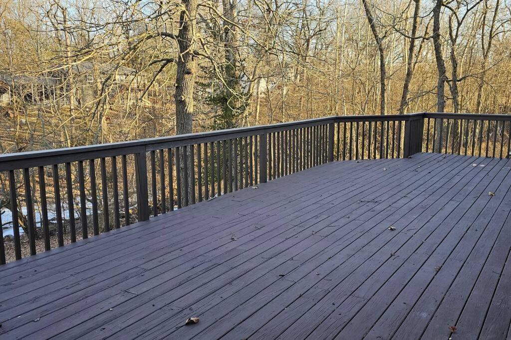 una terraza de madera con una valla negra y árboles en Entire Home w/ Free Wi-Fi, Garage, Deck, Yard, en Nixa