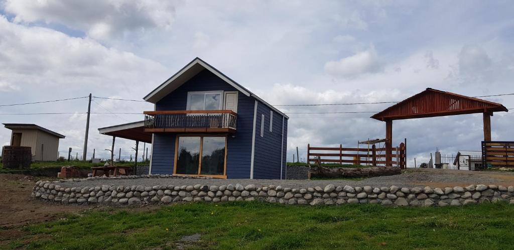 une petite maison bleue avec une terrasse couverte et une clôture dans l'établissement Rancho Eben Ezer, à Puyehue