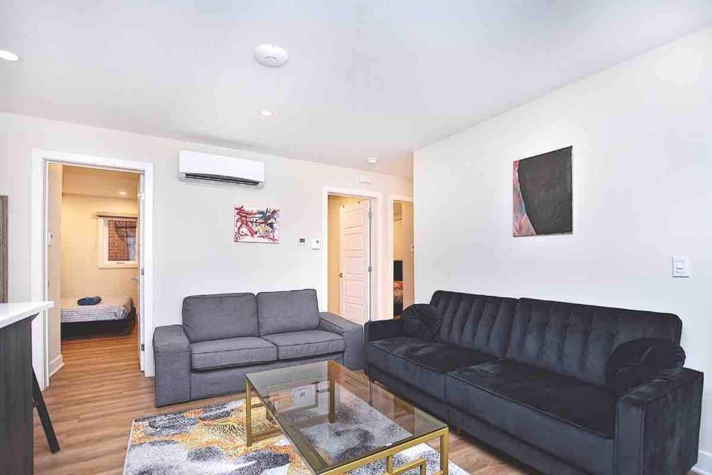 ein Wohnzimmer mit einem schwarzen Sofa und einem Tisch in der Unterkunft BEAU 4 CHAMBRES AU COEUR DU PLATEAU MONT-ROYAL in Montreal