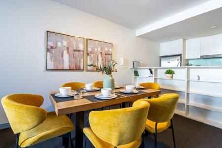 a dining room with a table and yellow chairs at Sleek Inner-City Getaway in Prime Location in Sydney
