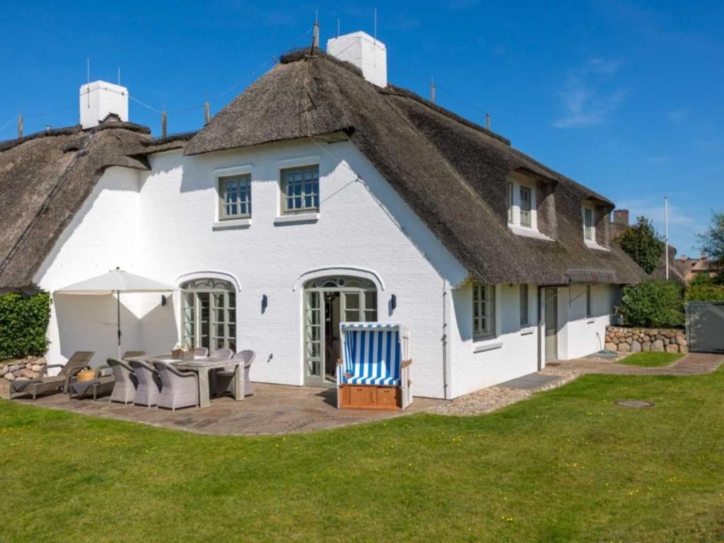 a large white house with a thatched roof at Leuchtturmblick Süd von Appartements & Mehr in Kampen