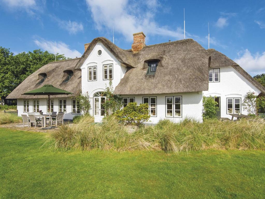 a large white house with a thatched roof at Moby Dick von Appartements & Mehr in Munkmarsch