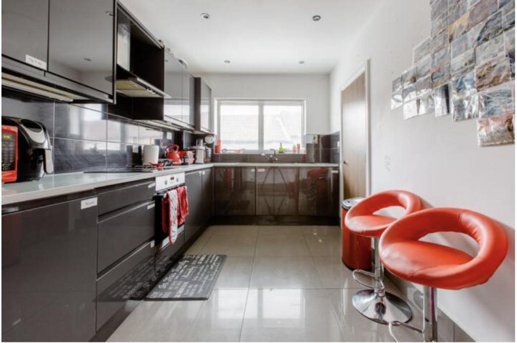 eine Küche mit einem roten Stuhl in der Küche in der Unterkunft Chic DuoRooms with Modern Comfort for Families in Kent