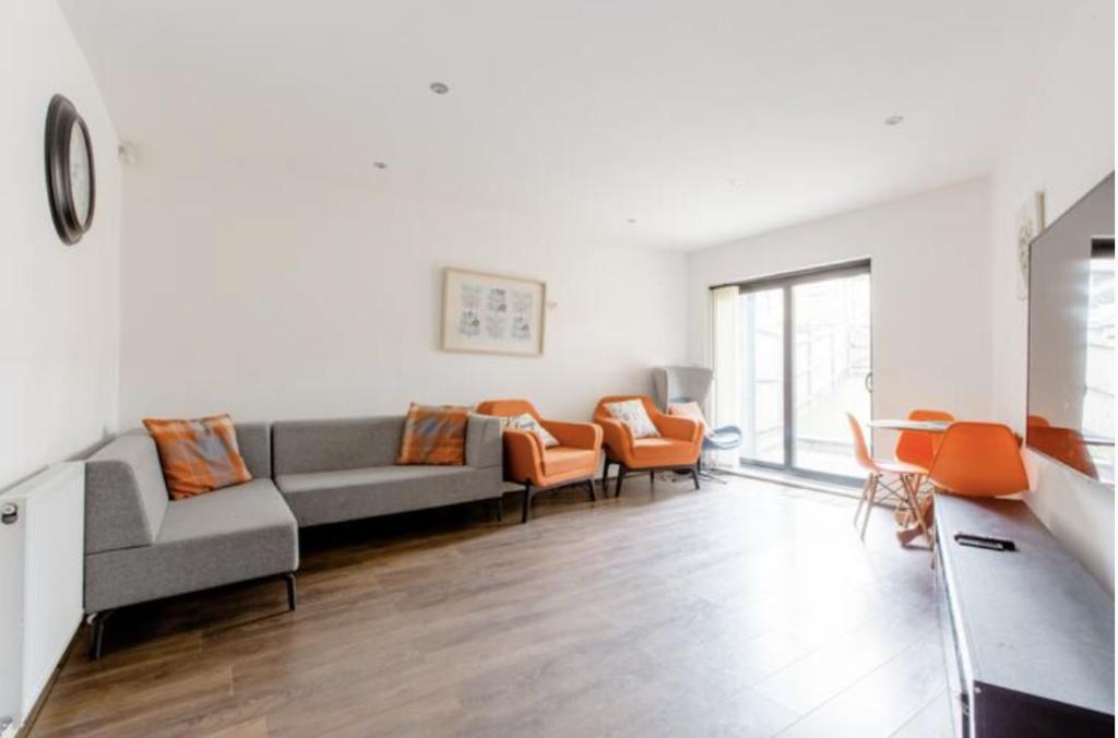 a living room with couches and orange chairs at Chic DuoRooms with Modern Comfort for Families in Kent