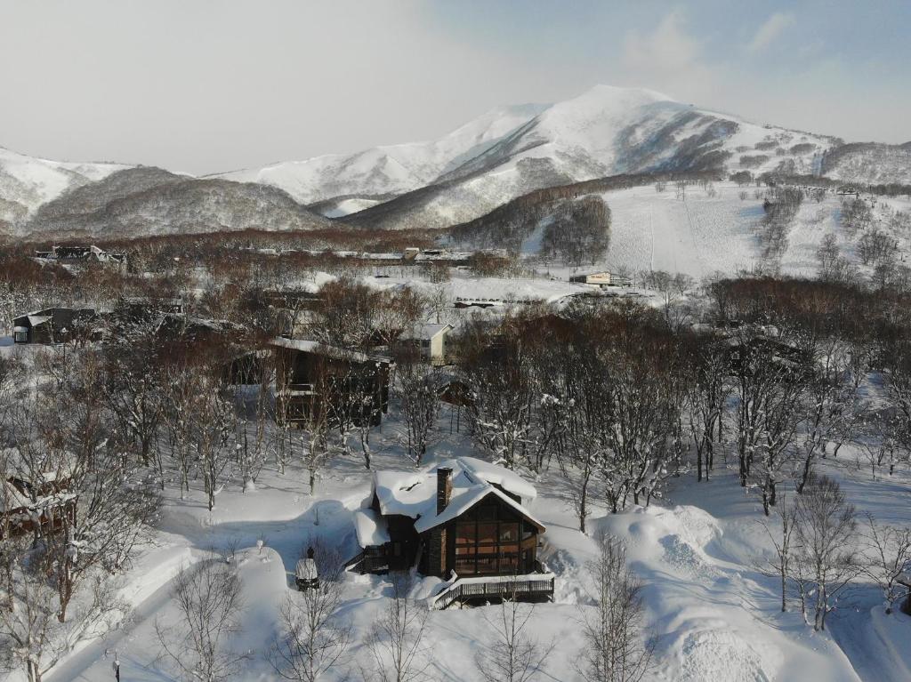 a cabin covered in snow with mountains in the background at Casa La Mount by Elite Havens in Niseko