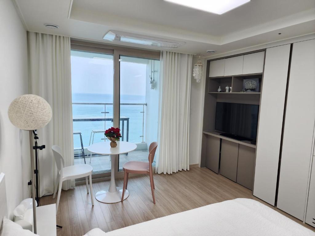 Sokcho Summitbay 1701 "Ocean View" في سوكشو: غرفة نوم مع طاولة وغرفة مطلة