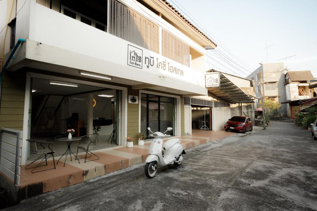 un scooter estacionado frente a un edificio en 2B Cozy Hostel ตรัง en Trang