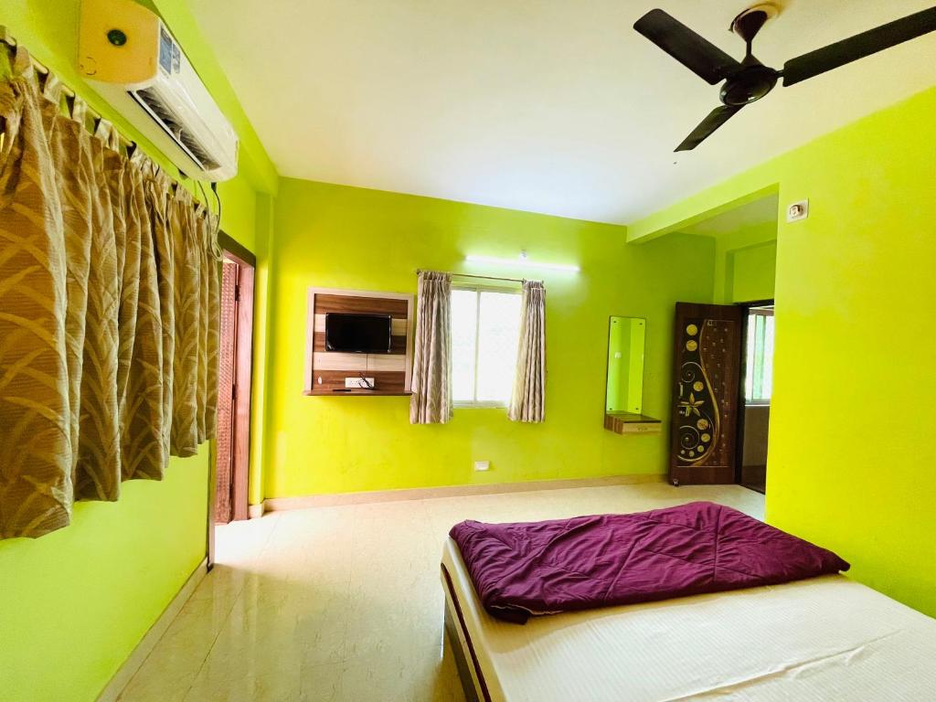 a bedroom with green walls and a bed with a ceiling at Hotel Falcon House ! Puri in Puri