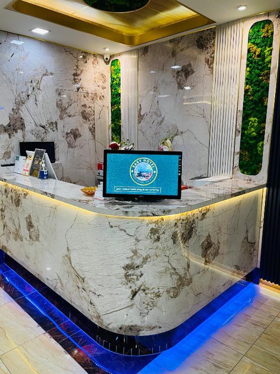 A marble-look reception desk with blue floor lighting and greenery behind it.