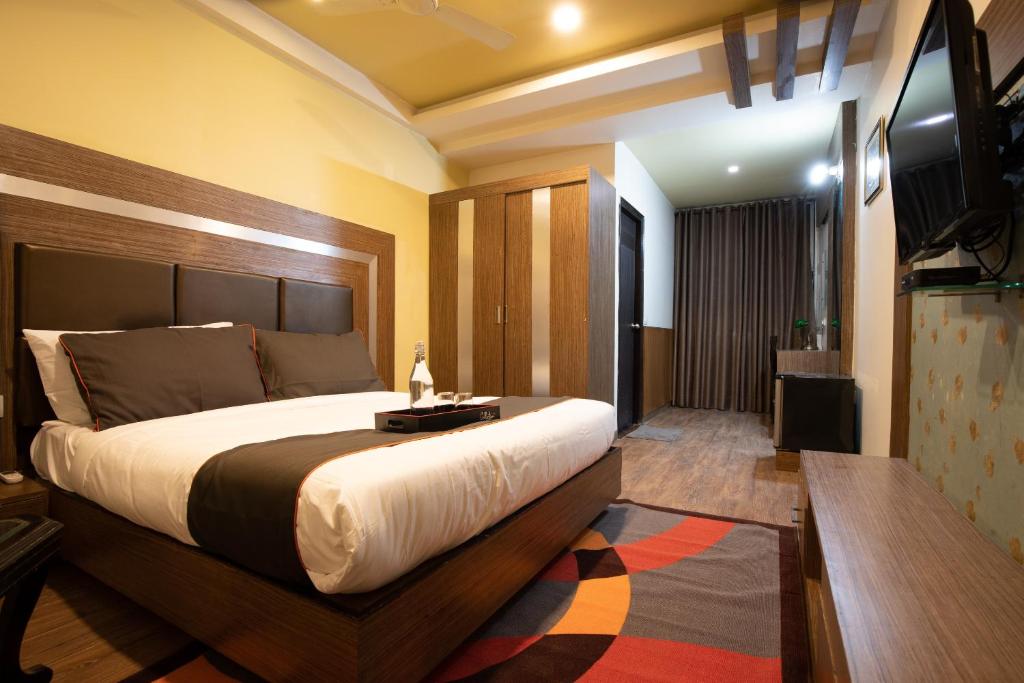 a bedroom with a large bed and a flat screen tv at Golden Avenue in Trivandrum