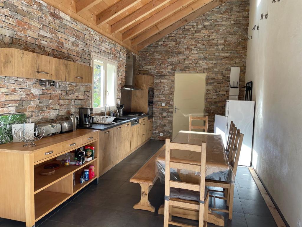 cocina con mesa de madera y pared de ladrillo en La Gardette en Le Freney-dʼOisans