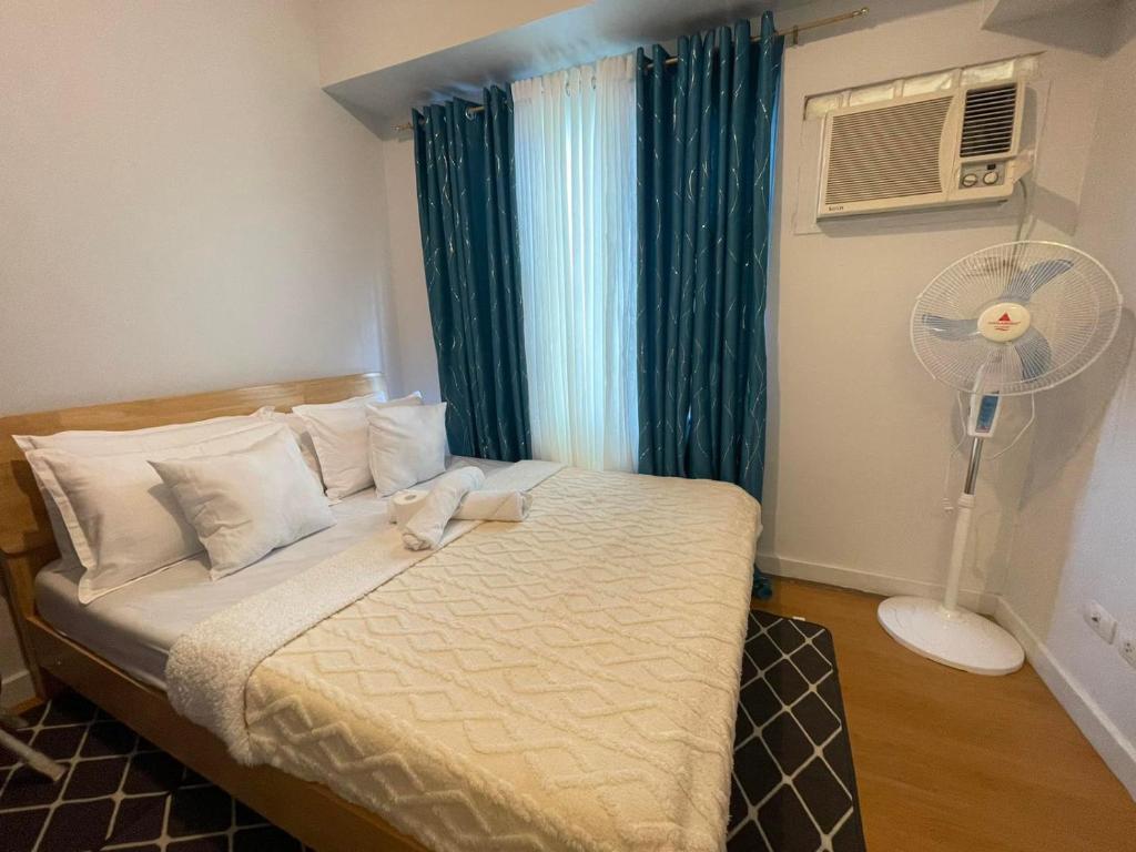 um quarto com uma cama, uma ventoinha e uma janela em 1 Bedroom Condo with Balcony in Ermita near the US Embassy and PGH em Manilla
