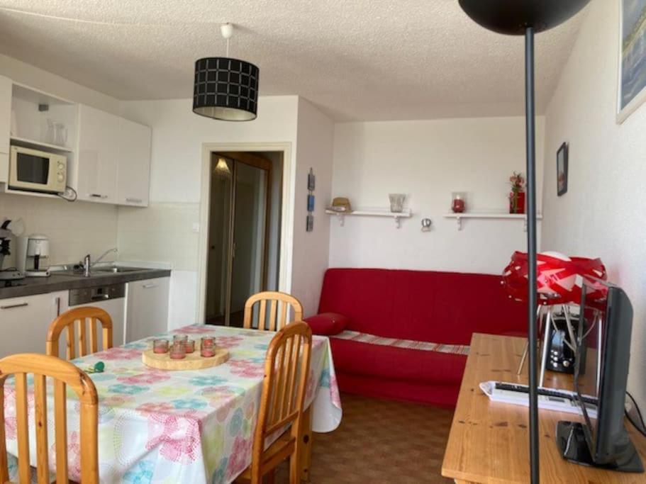 - une cuisine et une salle à manger avec une table et un canapé rouge dans l'établissement Appartement 308, Héliopolis K, au Cap d'Agde