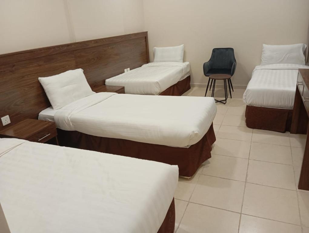 a room with three beds and a chair in it at فندق الساعي Alsai Hotel in Al ‘Utaybīyah