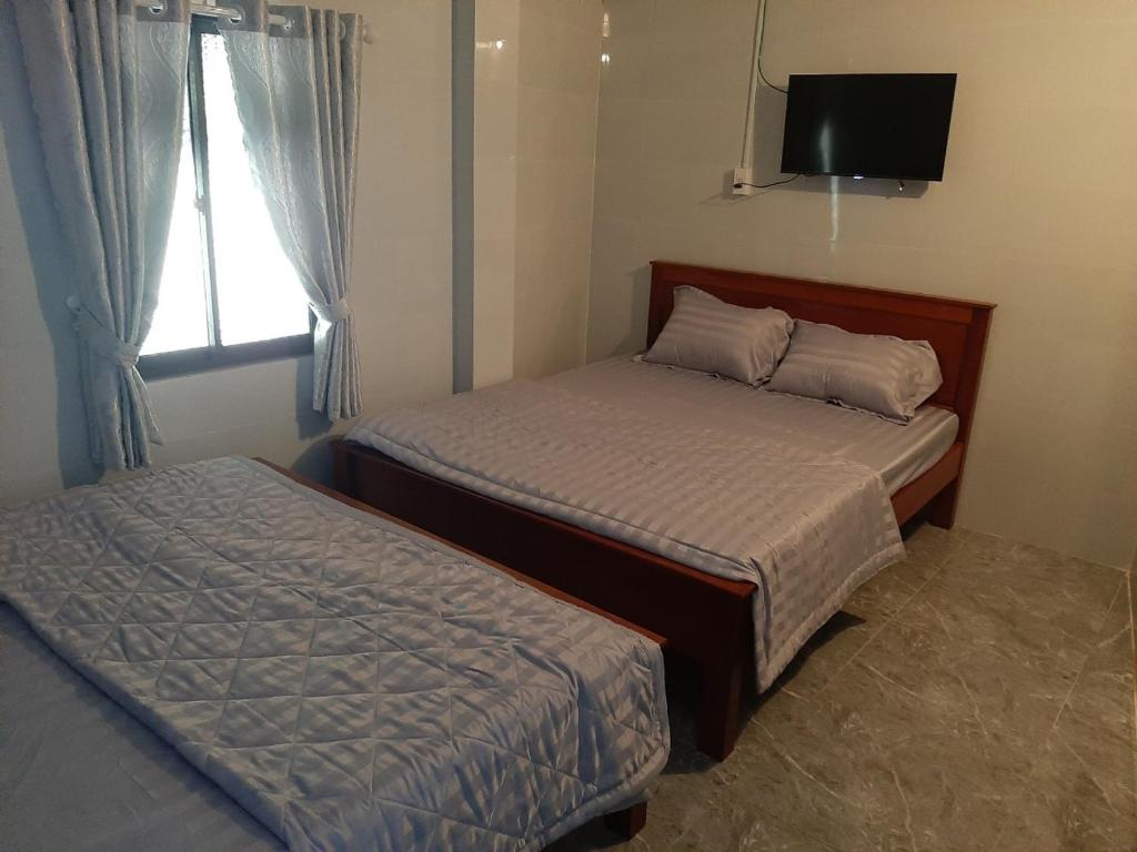 1 dormitorio con 2 camas, TV y ventana en Motel KIM PHÁT LUXURY - Núi Cấm, 