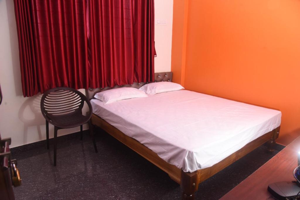 a small bedroom with a bed and a chair at Shiva Deluxe Lodge in Shimoga