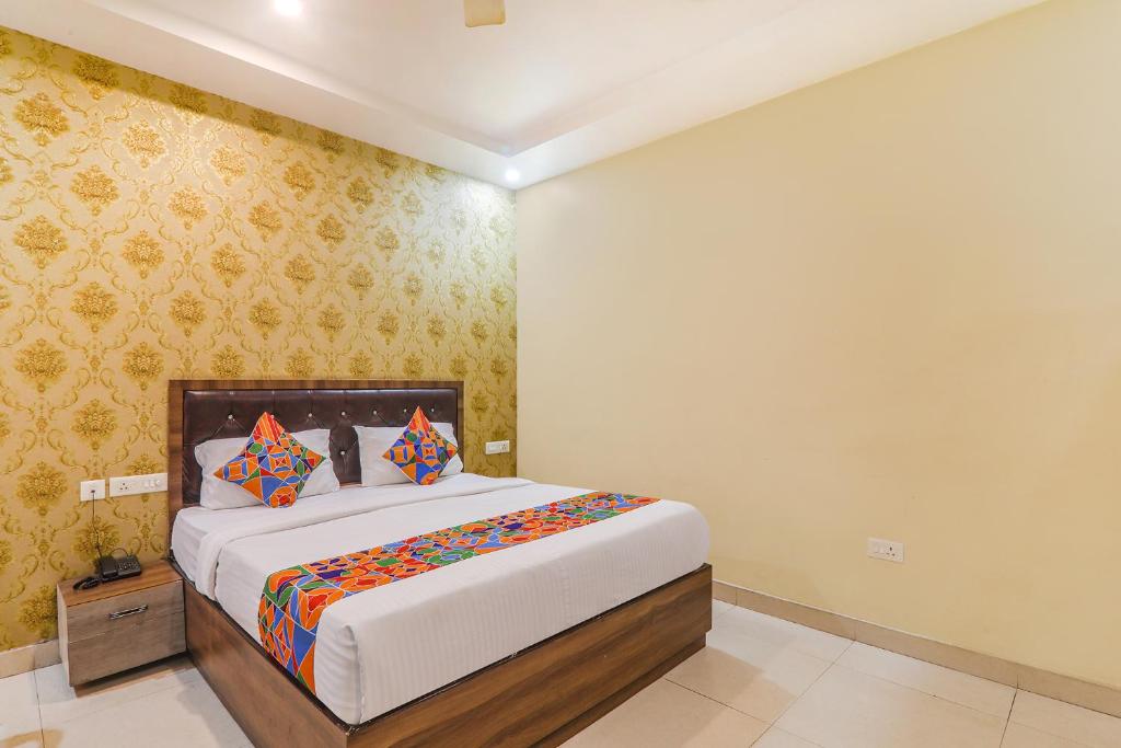 1 dormitorio con 1 cama grande y almohadas coloridas en FabExpress Grand Inn, en Vibhuti Khand