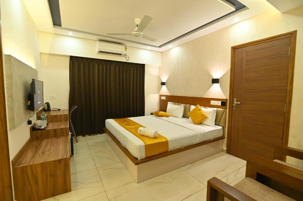 a hotel room with a bed and a television at Aurelia Comforts - Deralakatte in Mangalore