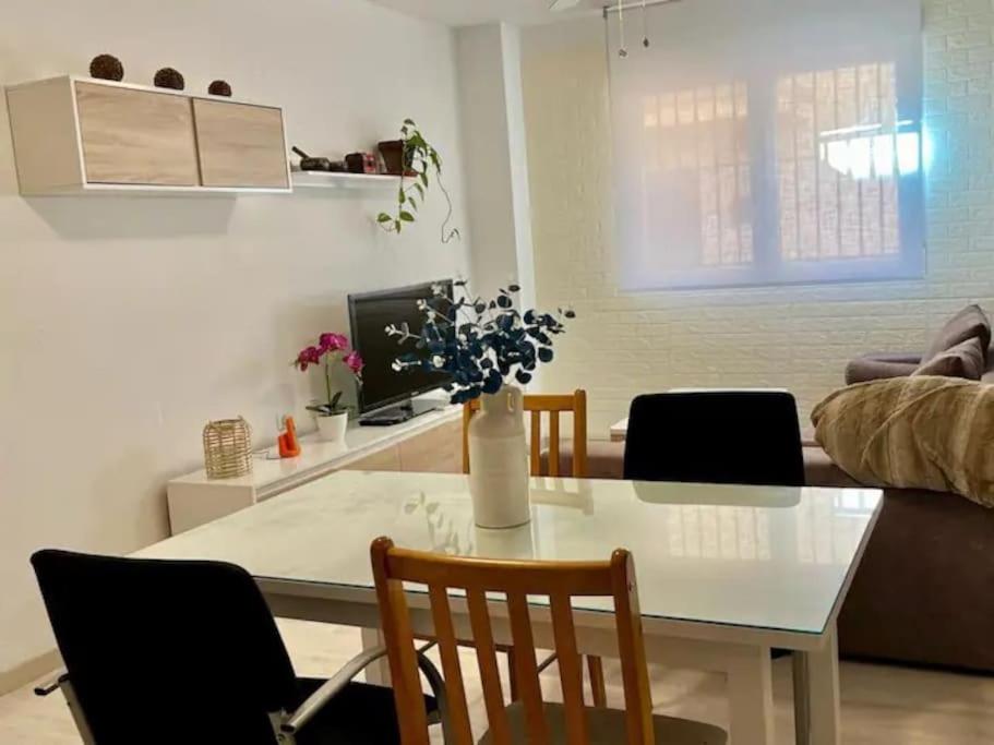 a dining room table with chairs and a vase with flowers at Apartamento Céntrico Churriana in Churriana de la Vega