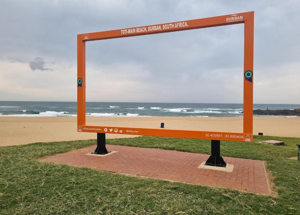 a sign at the beach with the ocean in the background at The Treehouse in Amanzimtoti