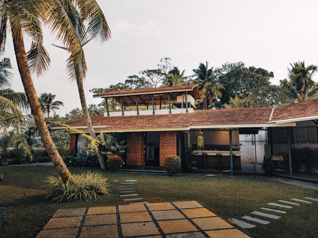 une maison avec un palmier en face dans l'établissement Bamboonest Riverside, à Ernakulam