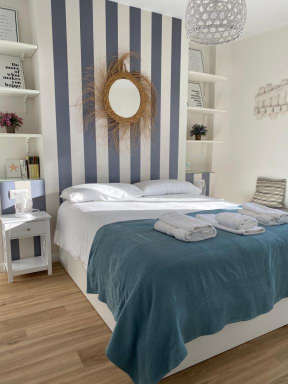 ein Schlafzimmer mit einem Bett mit einer blau-weißen gestreiften Wand in der Unterkunft Ático Al Sol en primera línea de playa in Rota