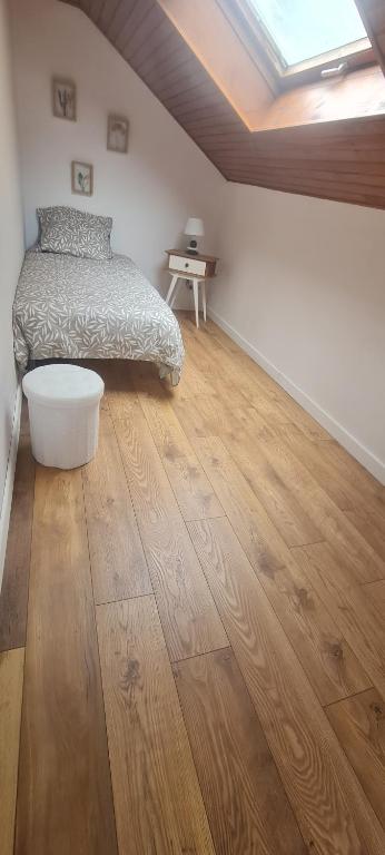 a bedroom with a bed and a wooden floor at gîte la tanière de claire in Ségur