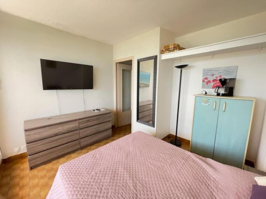 - une chambre avec un lit, une commode et une télévision dans l'établissement Studio 29, Héliopolis O au village naturiste, au Cap d'Agde