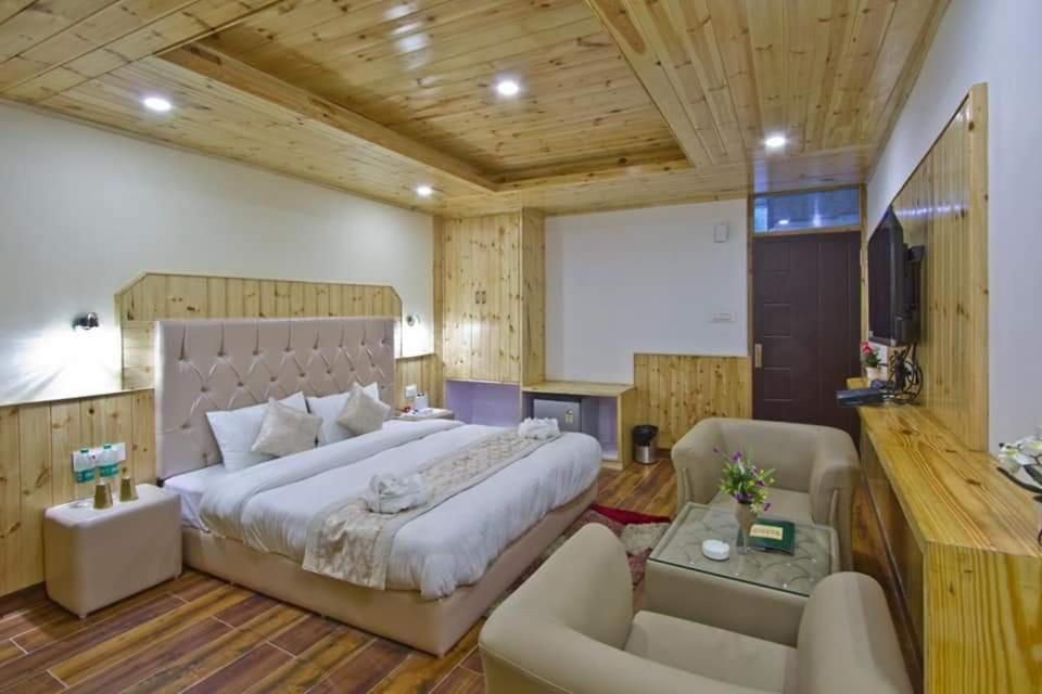 a bedroom with a large bed and a living room at Hotel Himalayan Classic, Manali in Manāli