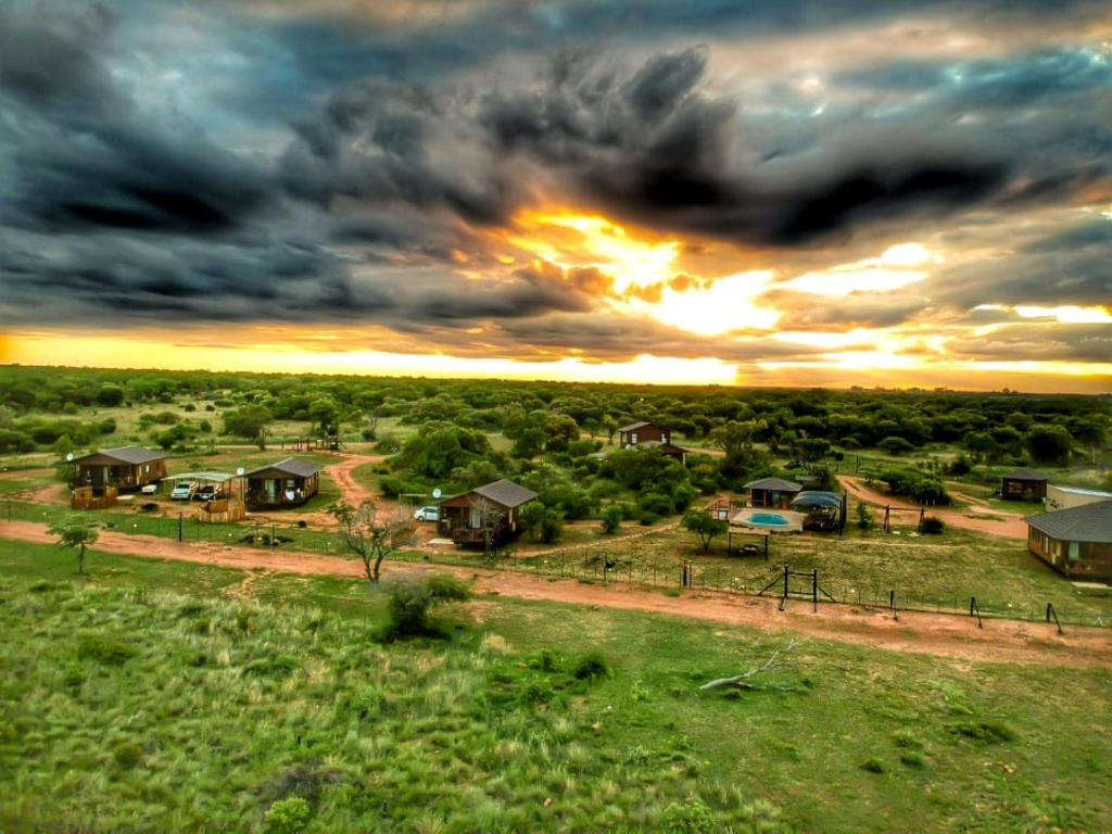 Pretoria的住宿－Abendruhe Lodge，享有房子的空中景色,背景是日落