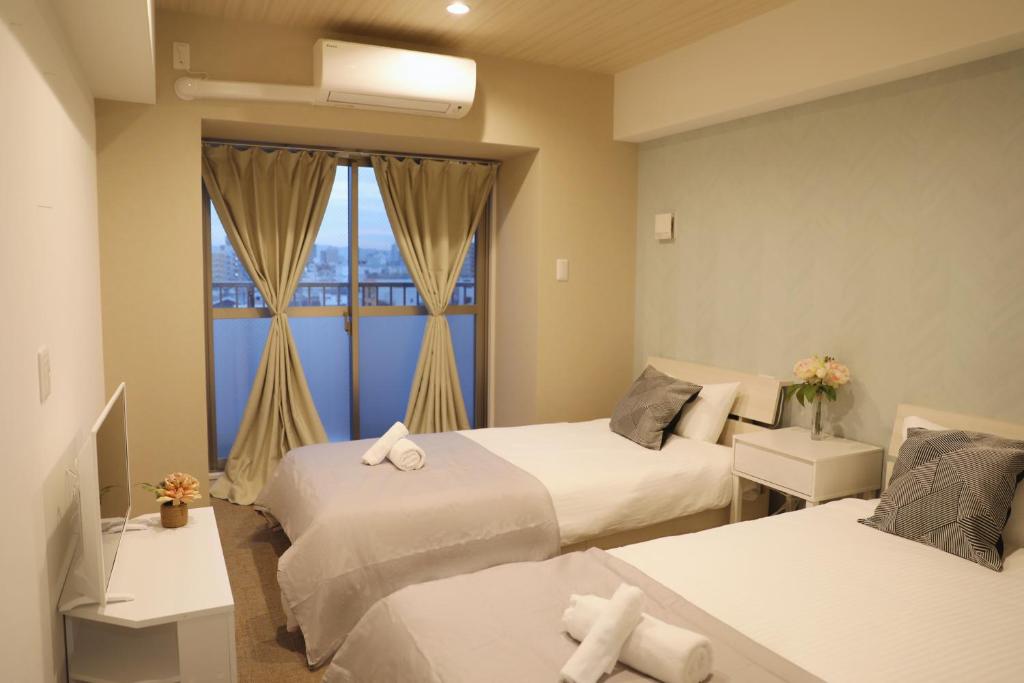 a hotel room with two beds and a window at Hoshino Stay 1 in Osaka
