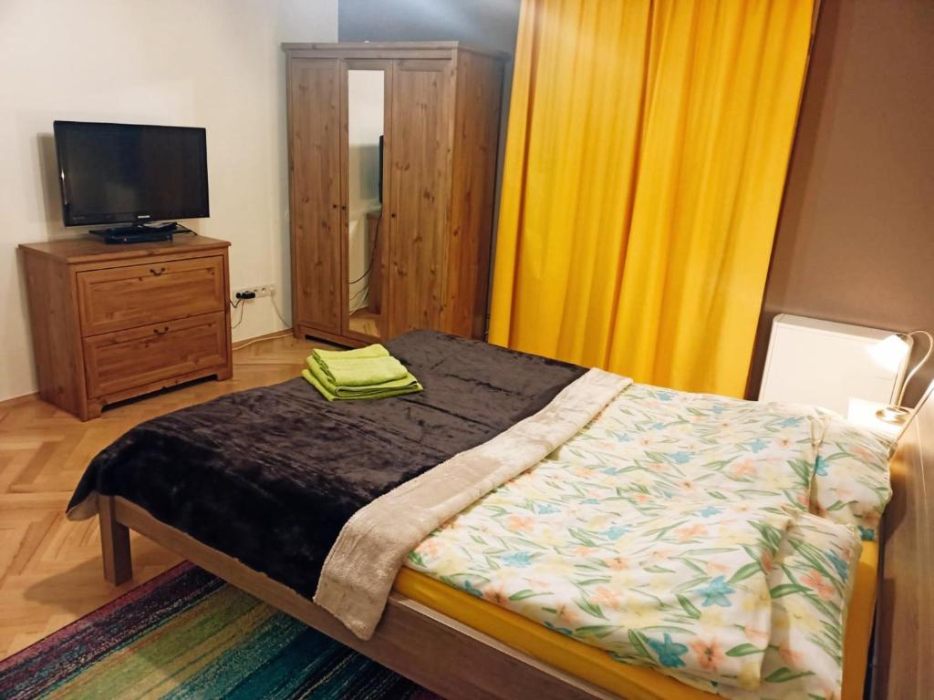 a bedroom with a bed and a tv and yellow curtains at Dex in Krakow
