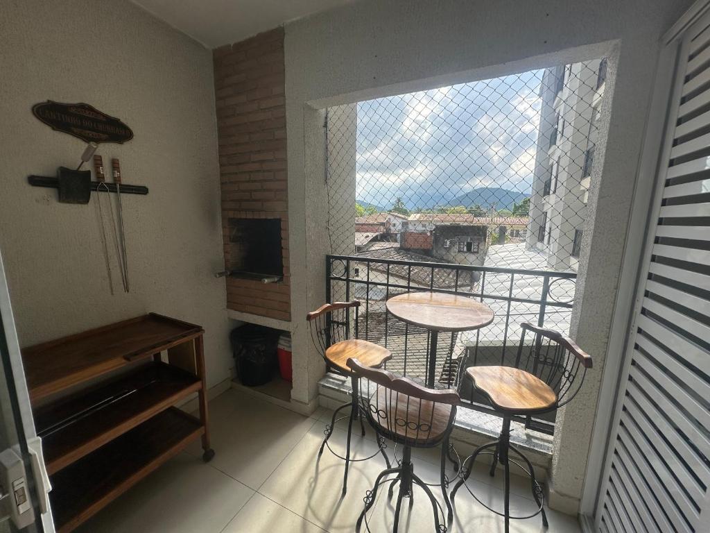 Zimmer mit einem Balkon mit Tisch und Stühlen in der Unterkunft Lindo Ap - CENTRO- piscina, churrasqueira gourmet, maquina lava e seca e wifi -edifício Jathy in Ubatuba