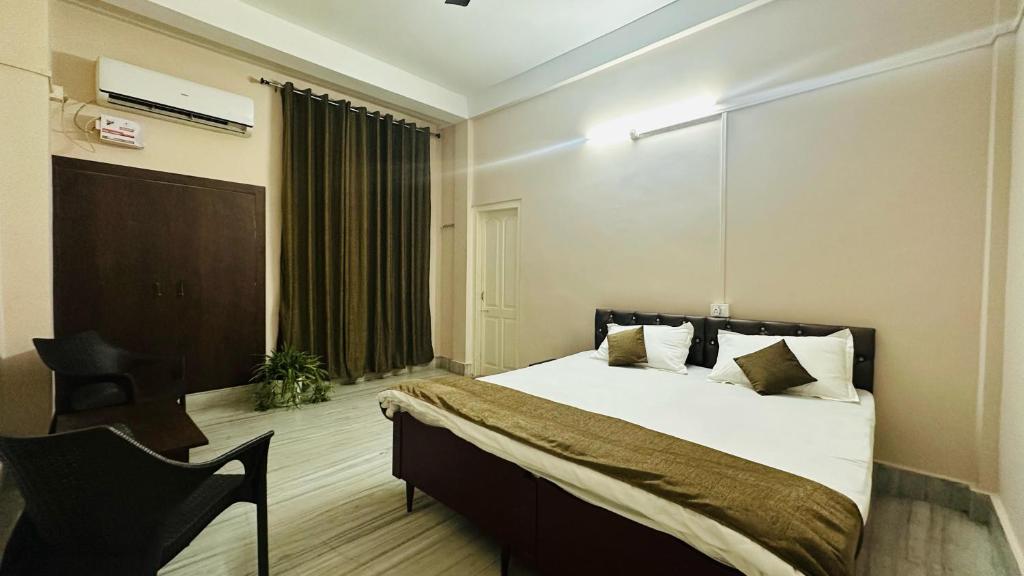 a bedroom with a large bed and a chair at N N residency in Sibsāgar
