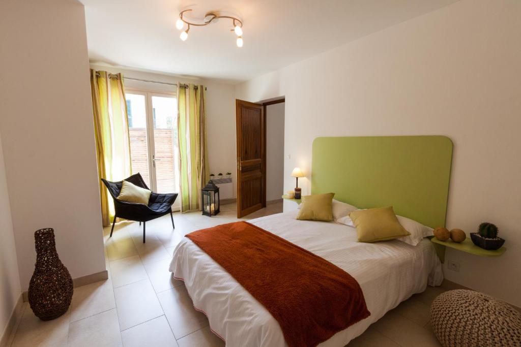 um quarto com uma cama com uma cabeceira verde e uma cadeira em Erbalunga - Résidence Les Bosquets - Cap corse Location em Brando