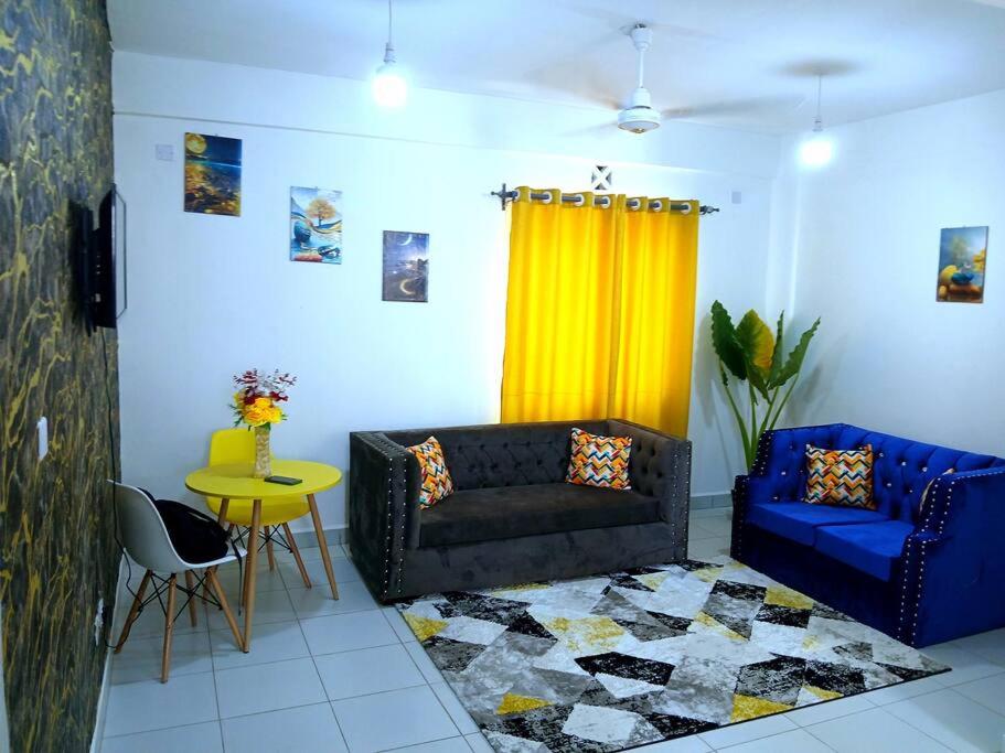 een woonkamer met een bank en een geel gordijn bij Double A Unique Homes in Mombasa