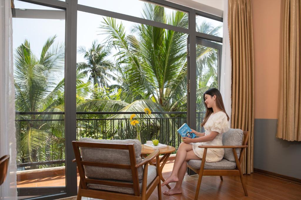 a woman sitting in a chair reading a book at Flower Villa in Hoi An