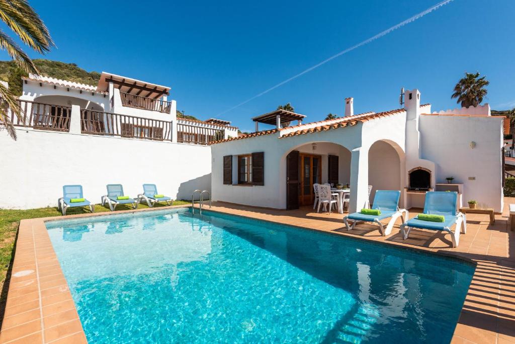 a villa with a swimming pool in front of a house at Villas Playas de Fornells in Fornells