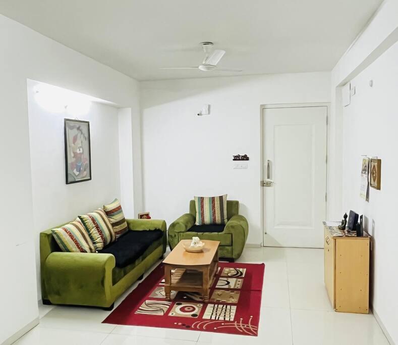 a living room with two green couches and a table at BRIJ Homes- 2 Bedroom Premium Apartment in Indore