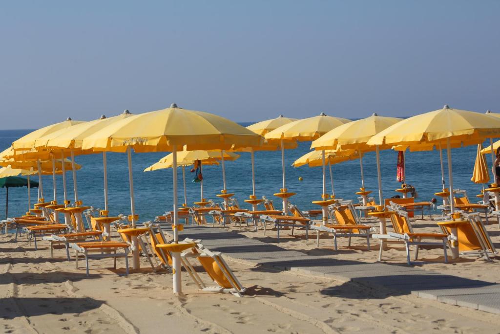 un montón de sillas y sombrillas en una playa en Marina del Marchese Beach Resort, en Botricello