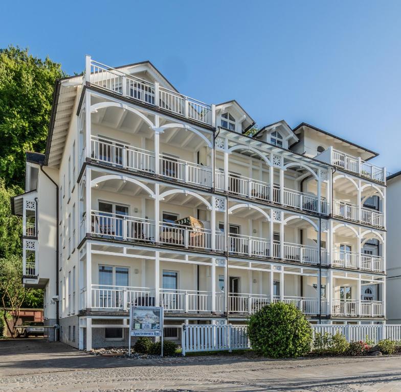 ein weißes Apartmenthaus mit Balkonen und Bäumen in der Unterkunft Villa Strandperle, App 13 - nur 20m zum Strand, TOPLAGE in Binz