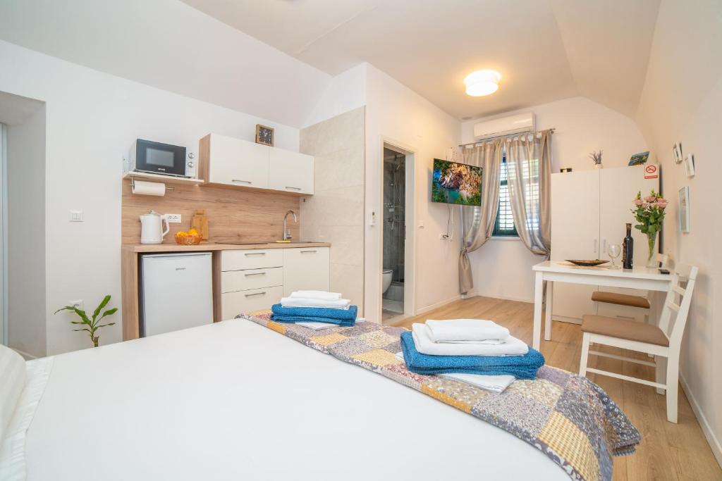 ein weißes Schlafzimmer mit einem Bett und einer Küche in der Unterkunft Studio apartment JELI in Cavtat