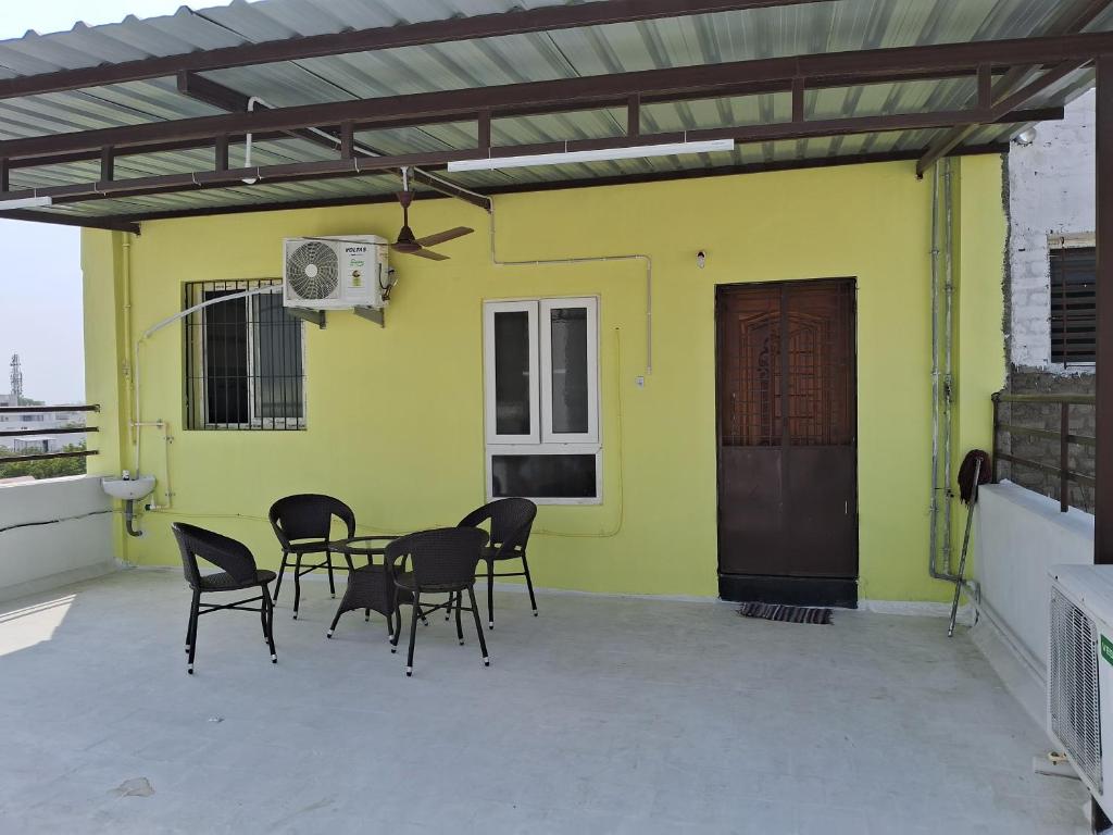 eine Terrasse mit Stühlen und einem Tisch vor einer gelben Wand in der Unterkunft PENTHOUSE APARTMENT in Madurai