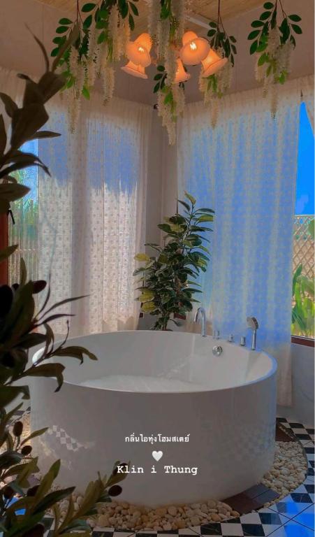 a bathroom with a white tub in front of a window at กลิ่นไอทุ่งโฮมสเตย์ in Ban Thum